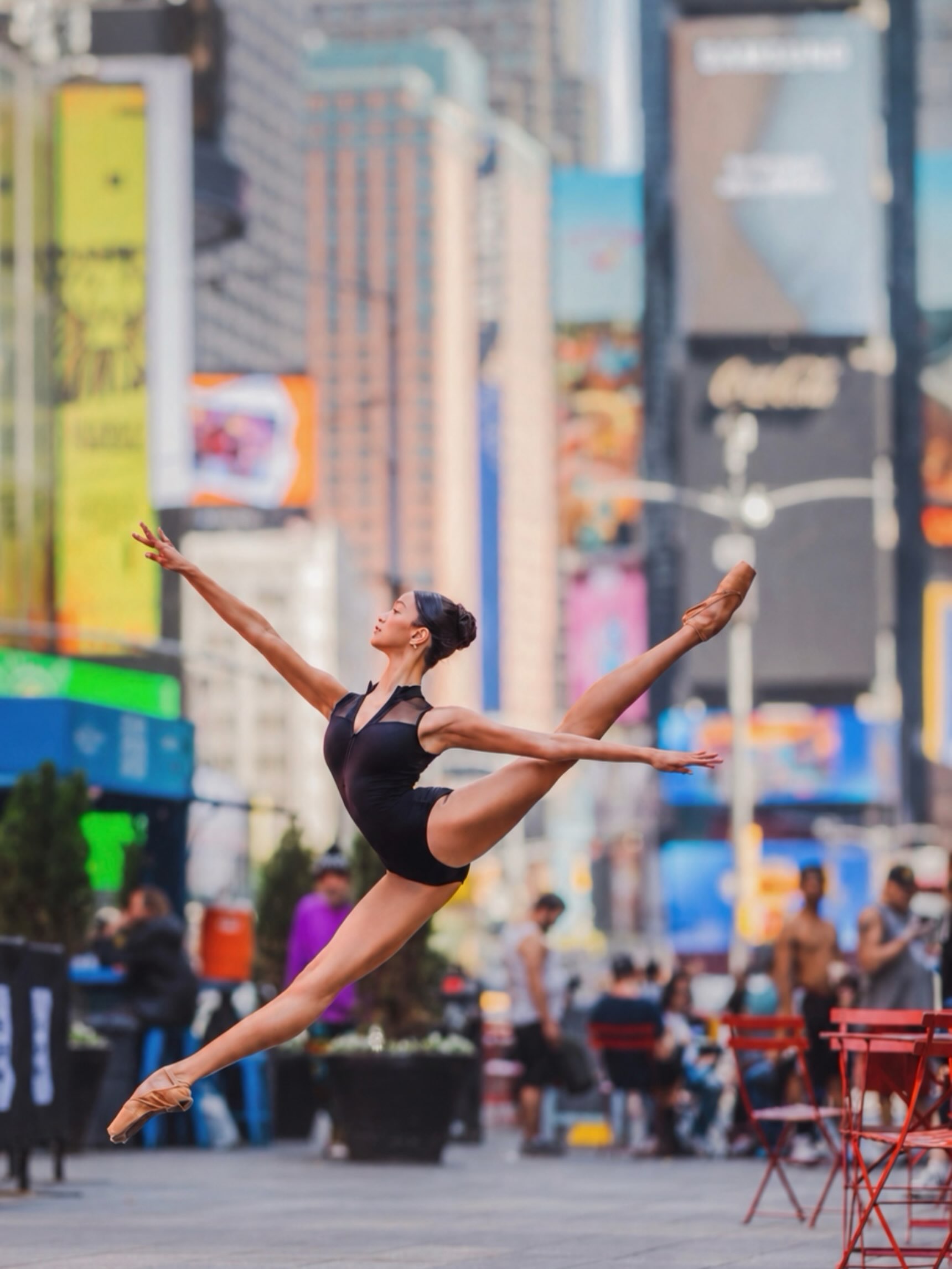 Grace Ramos suspended in a ballet leap in Times Square, with both arms and legs extended