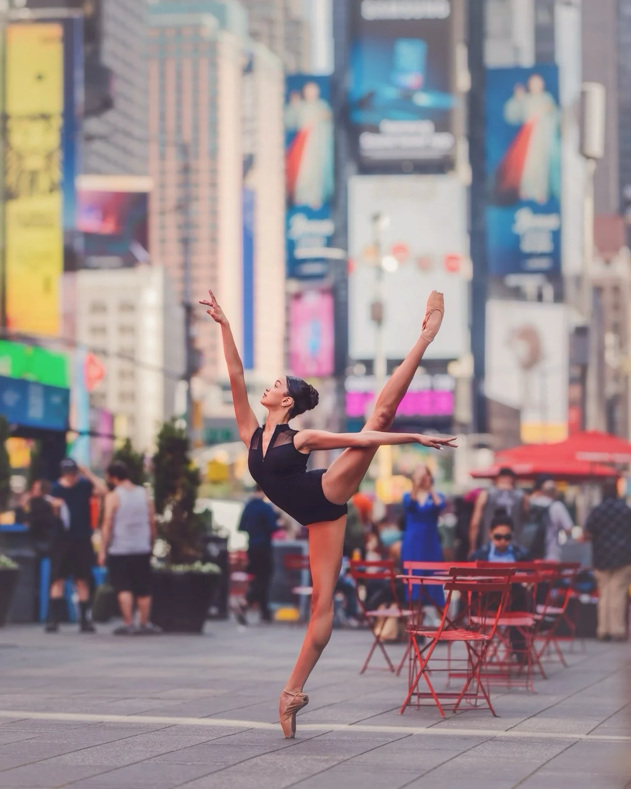 Grace en pointe in Times Square, with one leg extended high and her arms open